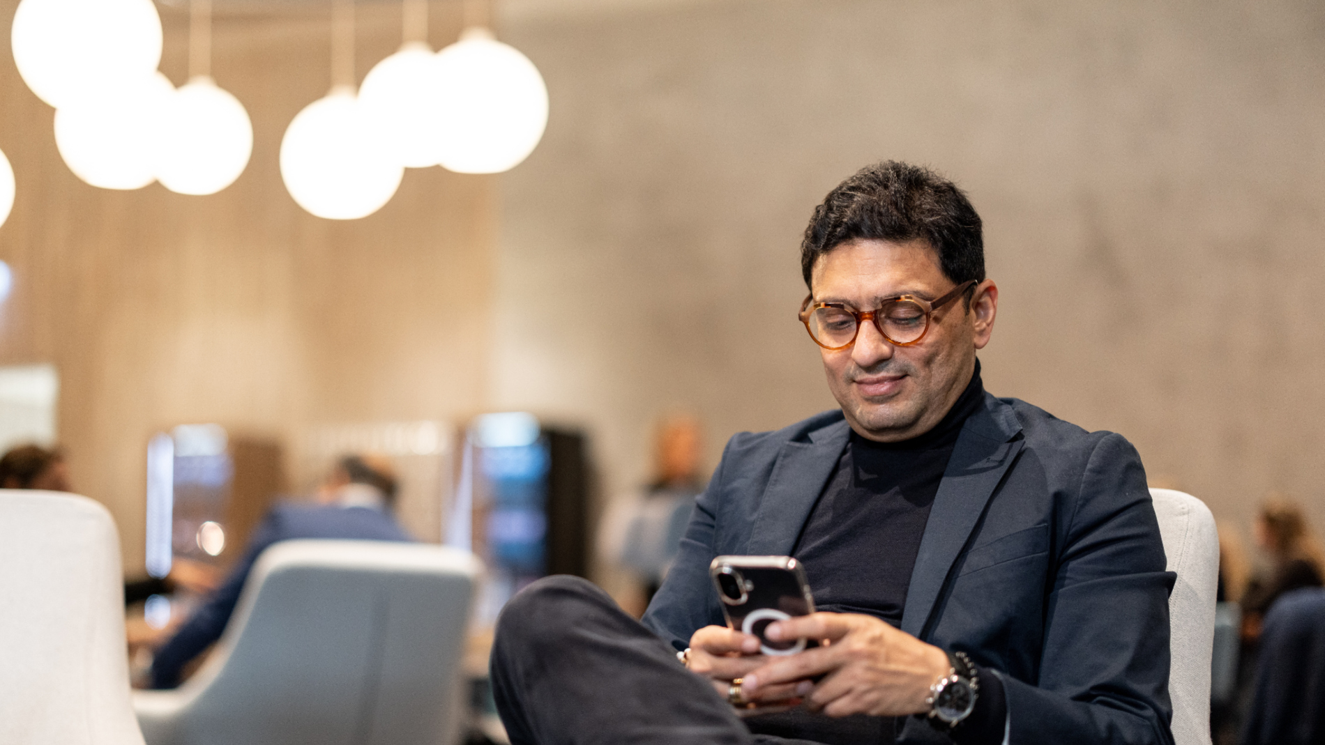 A man sits smiling in the Messe Frankfurt Business Club.