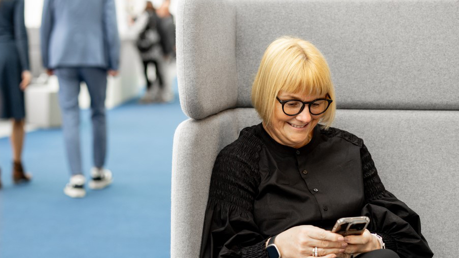 A woman sits smiling in the Messe Frankfurt Business Club.